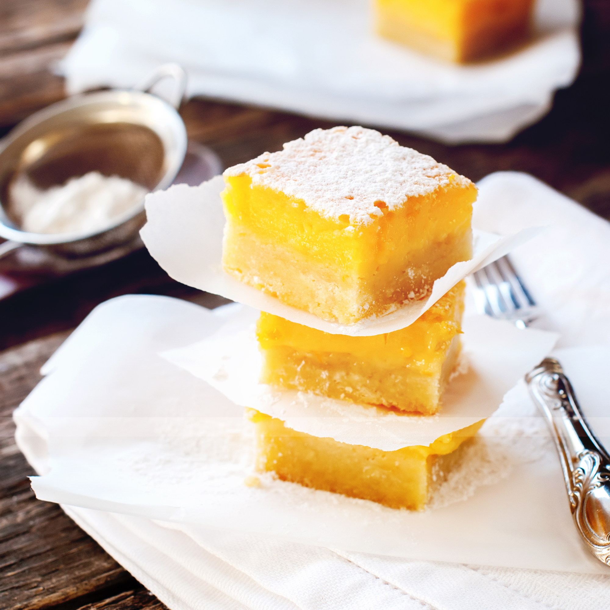 Baked Lemon Bars with Powdered Sugar Peaces in Tower Stack Wooden Table
