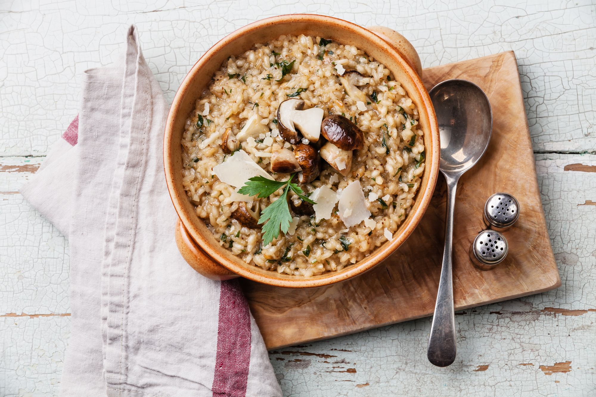 Risotto with wild mushrooms with parsley and parmesan on olive wood board