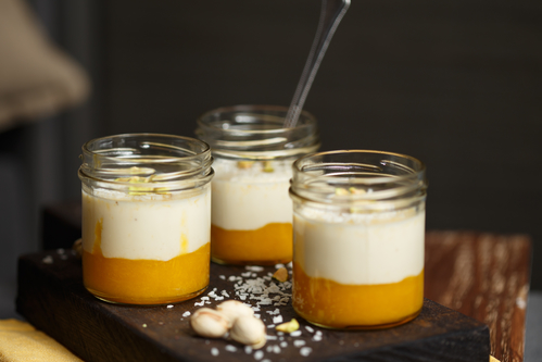Panna cotta with mango, coconut and pistachios on a wooden cutting board