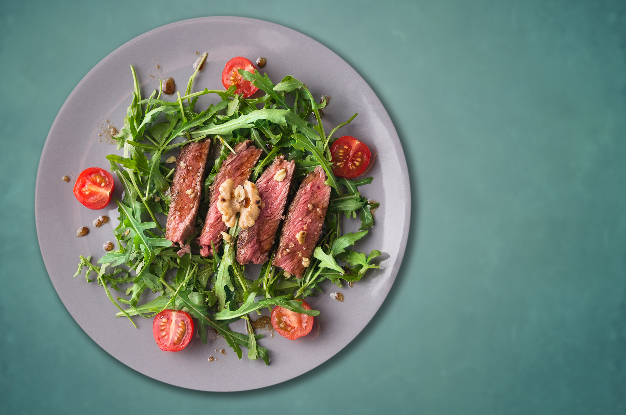 beef steak medium, Ruccola salad with tomatoes and walnuts,gray plate, blue background,copy space