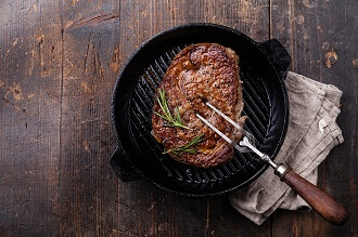 Grilled Black Angus Steak and meat fork on grill iron pan on wooden background